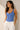 Maillot de bain une pièce bleu à rayures verticales porté par une femme avec un pantalon blanc